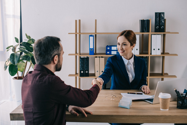 smiling businesswoman client shaking hands meeting office